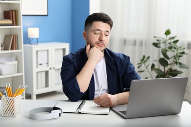 Photo of Man taking notes during online lesson at desk indoors. Self-study