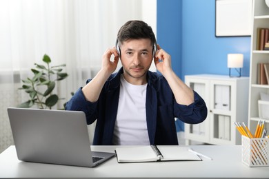 Photo of Man learning online using laptop at desk indoors. Self-study