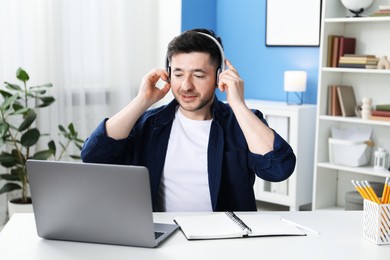 Photo of Man learning online using laptop at desk indoors. Self-study