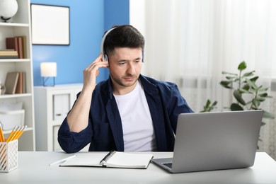 Photo of Man learning online using laptop at desk indoors. Self-study