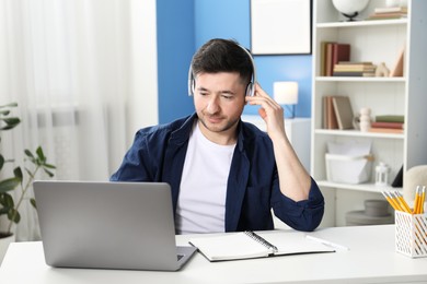 Photo of Man learning online using laptop at desk indoors. Self-study