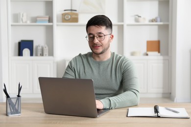 Photo of Man learning online using laptop at desk indoors. Self-study