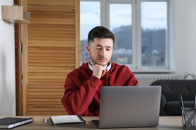 Photo of Man learning online using laptop at desk indoors. Self-study