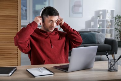 Photo of Man learning online using laptop at desk indoors. Self-study