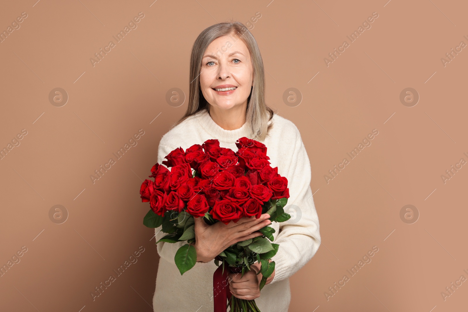 Photo of Smiling woman with bouquet of roses on beige background