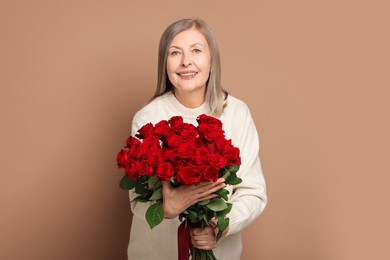 Photo of Smiling woman with bouquet of roses on beige background