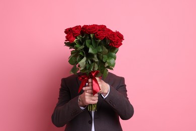 Photo of Senior man with bouquet of red roses on pink background