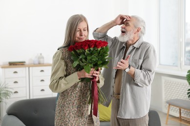 Photo of Cute couple with bouquet of red roses at home