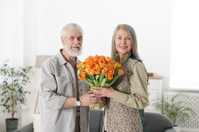 Photo of Happy couple with bouquet of tulips at home