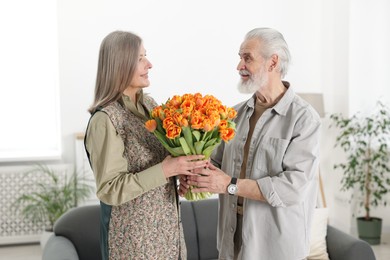 Photo of Happy couple with bouquet of tulips at home