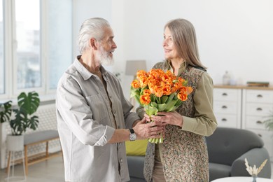 Photo of Happy couple with bouquet of tulips at home