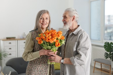 Photo of Happy couple with bouquet of tulips at home