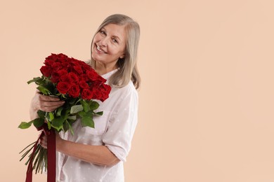 Photo of Smiling woman with bouquet of roses on beige background. Space for text