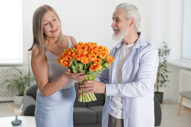 Photo of Happy couple with bouquet of tulips at home