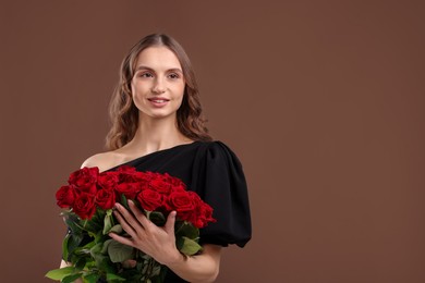 Photo of Smiling woman with bouquet of roses on brown background. Space for text