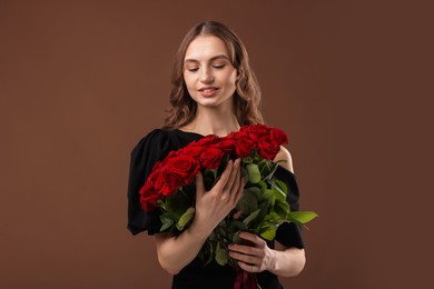 Photo of Smiling woman with bouquet of roses on brown background. Space for text