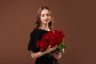 Photo of Smiling woman with bouquet of roses on brown background