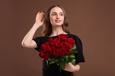 Photo of Smiling woman with bouquet of roses on brown background