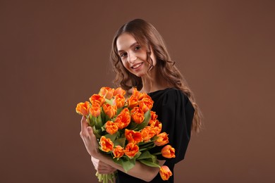 Photo of Smiling woman with bouquet of tulips on brown background