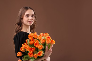 Photo of Smiling woman with bouquet of tulips on brown background. Space for text