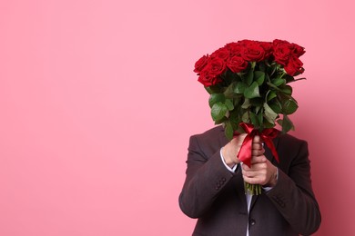 Photo of Senior man with bouquet of red roses on pink background, space for text