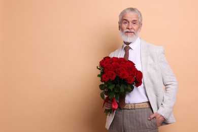 Photo of Senior man with bouquet of red roses on beige background, space for text