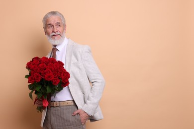 Photo of Senior man with bouquet of red roses on beige background, space for text