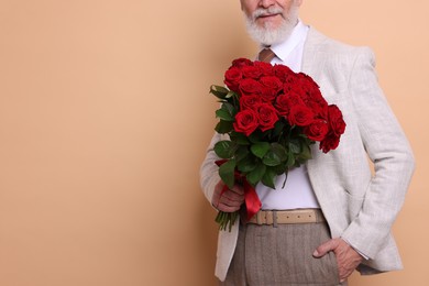 Photo of Senior man with bouquet of red roses on beige background, closeup. Space for text