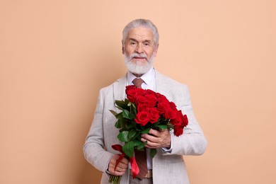 Photo of Senior man with bouquet of red roses on beige background