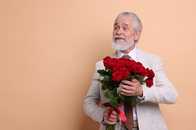 Photo of Senior man with bouquet of red roses on beige background, space for text