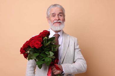 Photo of Senior man with bouquet of red roses on beige background