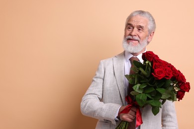 Photo of Senior man with bouquet of red roses on beige background, space for text