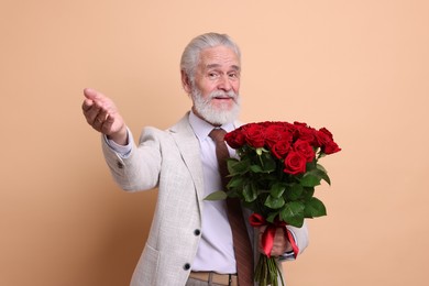 Photo of Senior man with bouquet of red roses on beige background