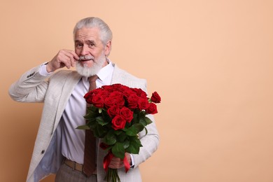 Photo of Senior man with bouquet of red roses on beige background, space for text