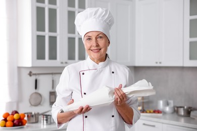 Photo of Professional pastry chef with frosting bag full of cream in kitchen