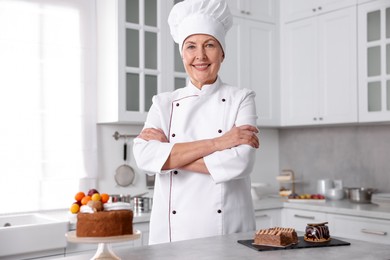 Photo of Professional pastry chef with desserts at table in kitchen