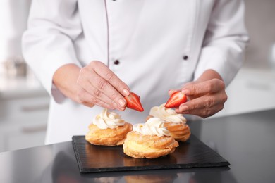 Photo of Professional pastry chef making desserts at table in kitchen, closeup