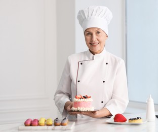 Photo of Professional pastry chef with desserts at table in kitchen