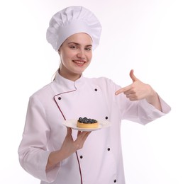 Photo of Happy confectioner in uniform holding delicious tart with blueberries on white background