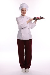 Photo of Happy confectioner in uniform holding delicious eclairs on white background