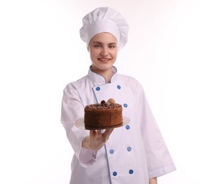 Photo of Happy confectioner in uniform holding delicious chocolate cake on white background