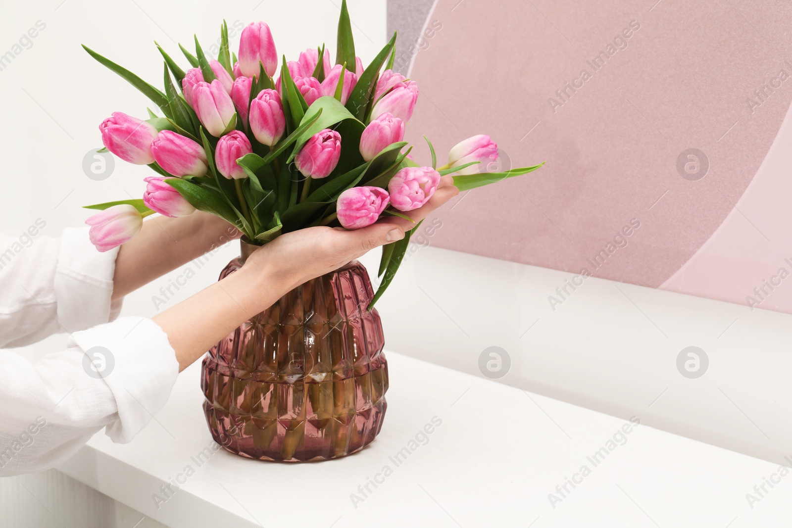 Photo of Woman with bouquet of beautiful tulips near window sill indoors, closeup. Space for text