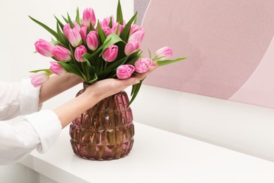 Photo of Woman with bouquet of beautiful tulips near window sill indoors, closeup. Space for text