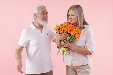 Photo of Cute couple with bouquet of tulips on pink background