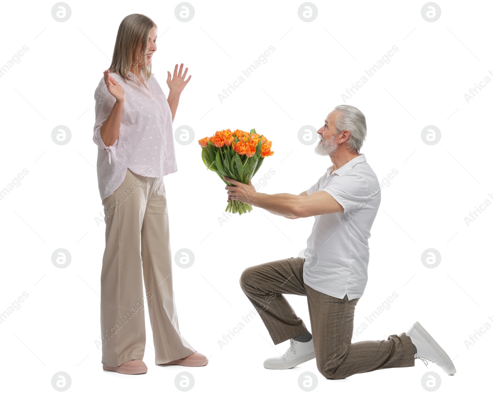 Photo of Man presenting bouquet of tulips to his happy wife on white background