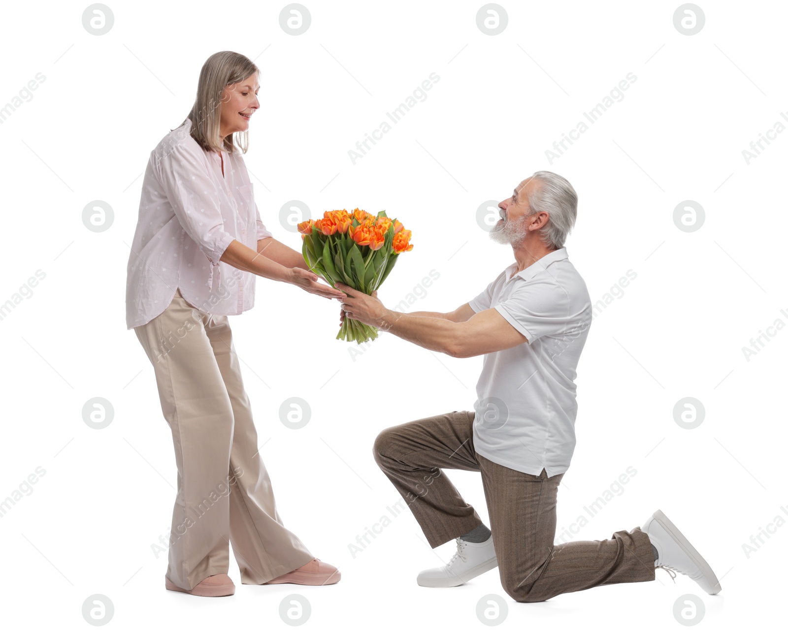 Photo of Man presenting bouquet of tulips to his happy wife on white background