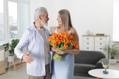 Photo of Happy couple with bouquet of tulips at home