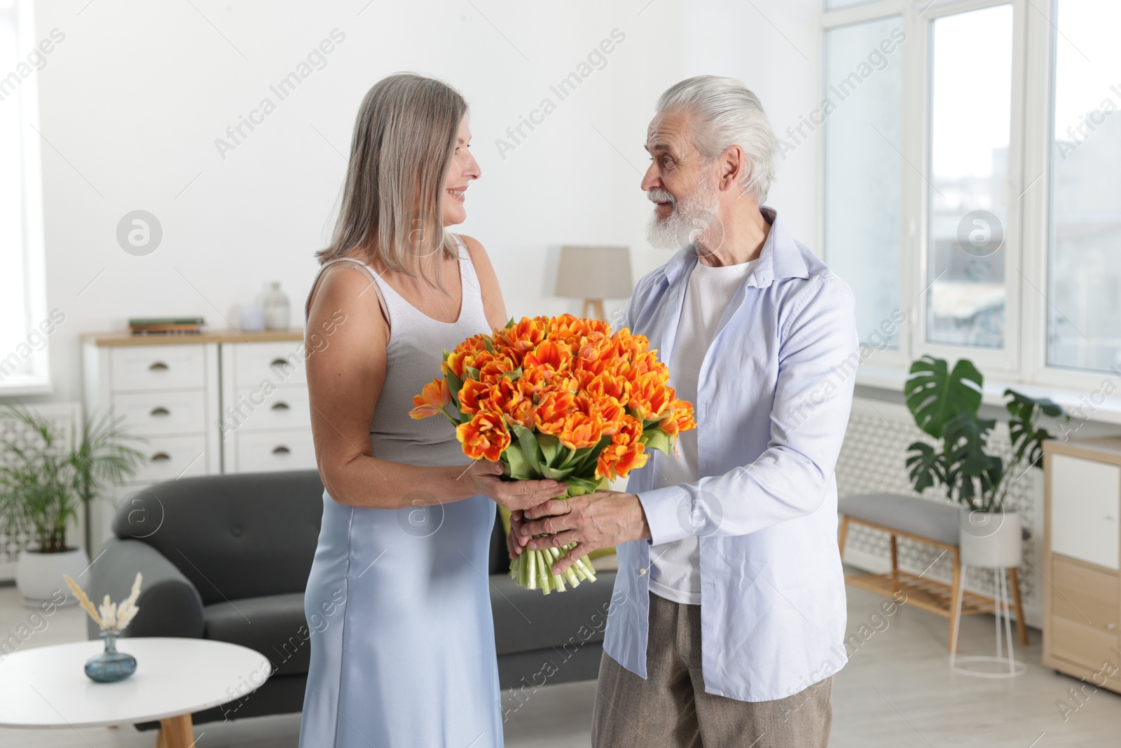 Photo of Happy couple with bouquet of tulips at home