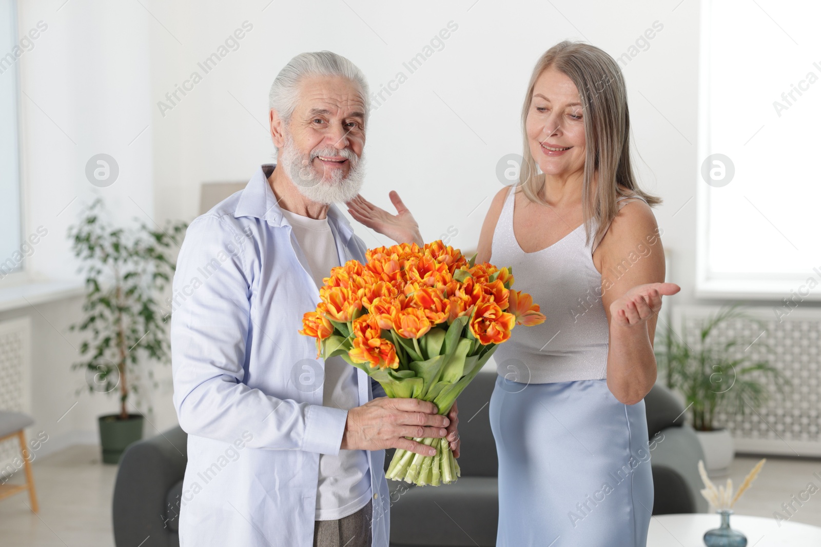 Photo of Happy couple with bouquet of tulips at home