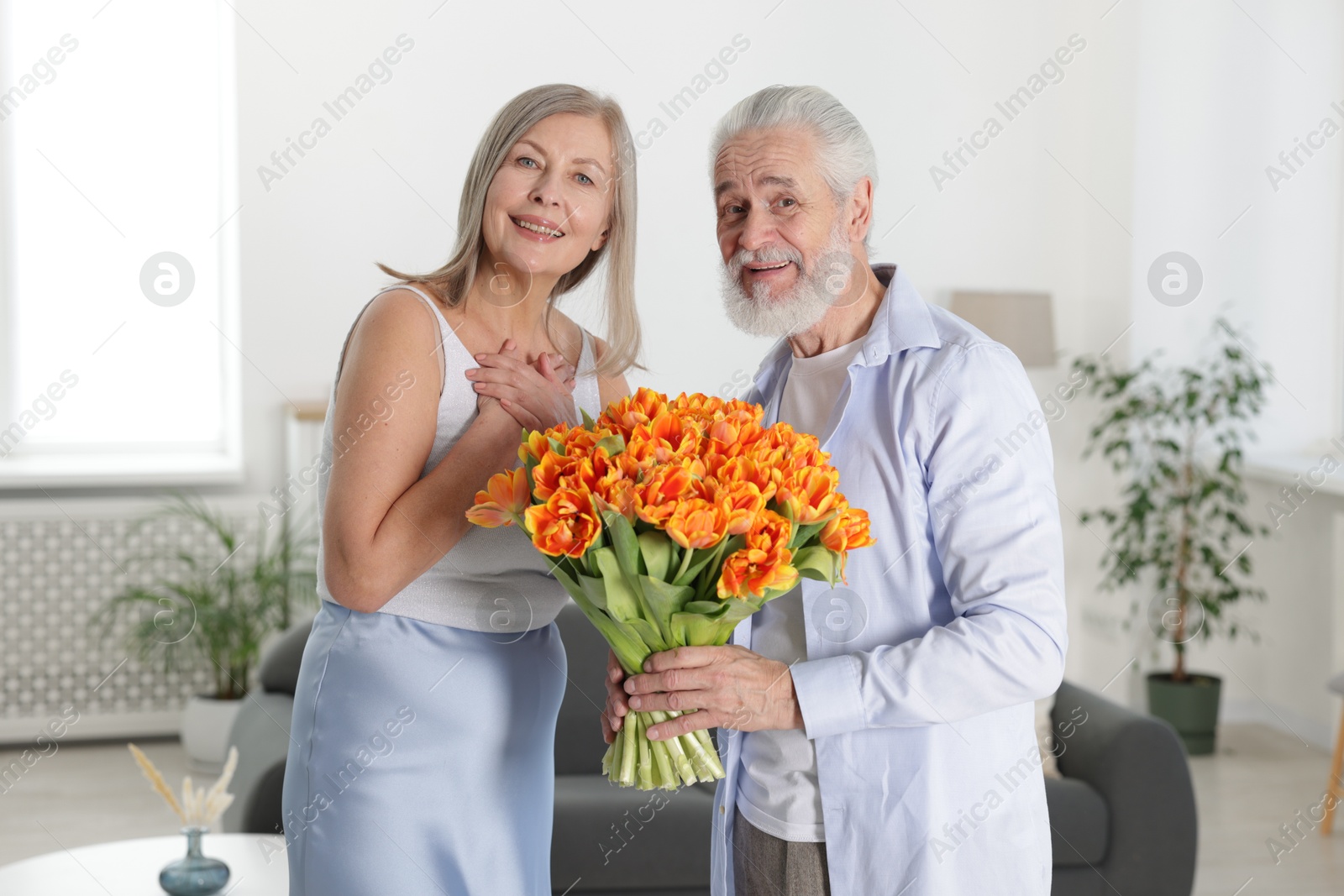 Photo of Happy couple with bouquet of tulips at home